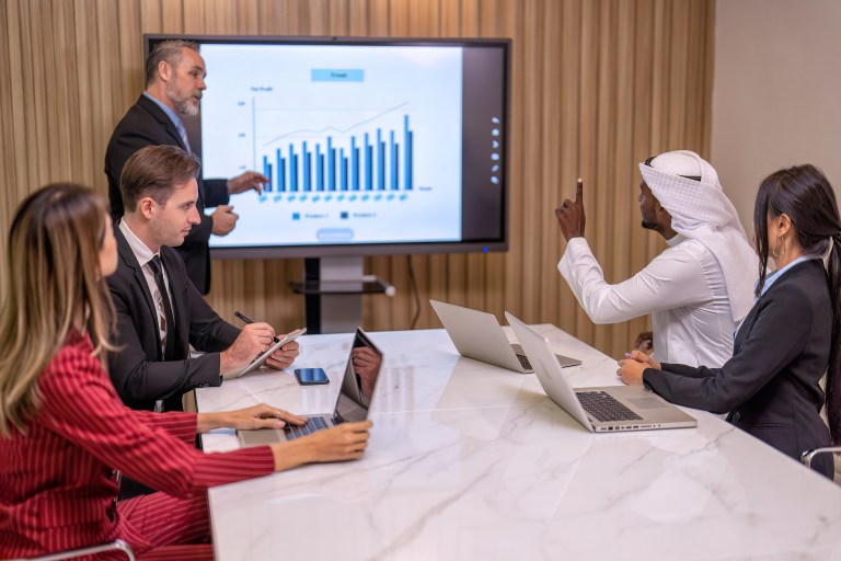 T2G - Group of business diversity people and middle east co-worker working in office in the meeting room one employee stand near big screen TV presentation explain the business plan to team