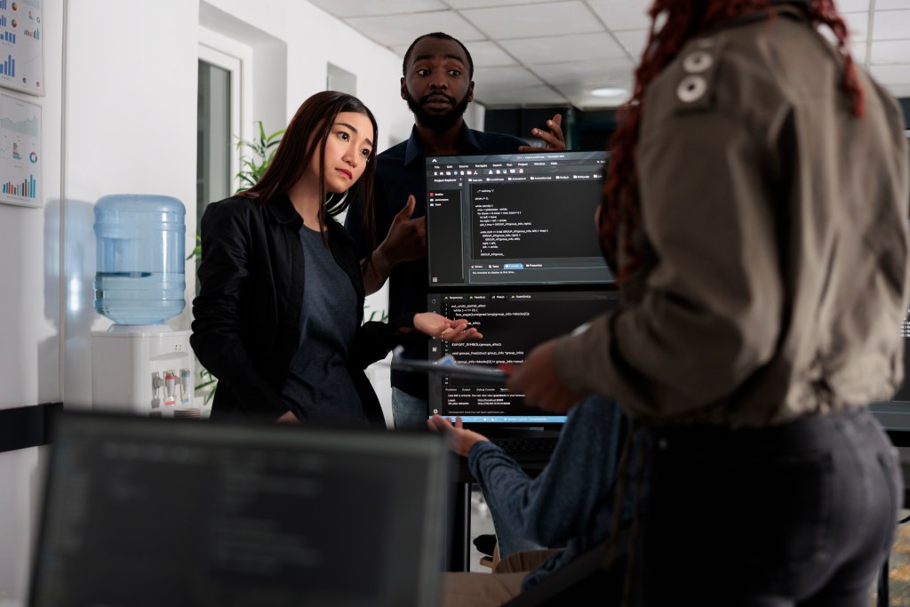 T2G - Software engineers collaborating on coding project talking about programming algorithm for new cloud computing user interface. Diverse team of web developer running database system code.
