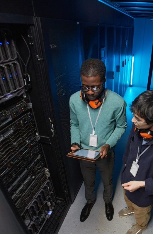 T2G - High angle view at two young technicians setting up server network while working in data center, copy space