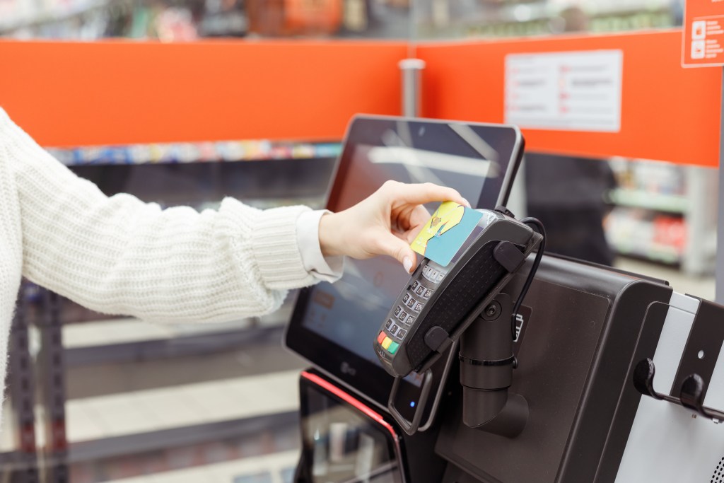 Customer woman buys and pays at checkout of self-service vending machine in a modern supermarket