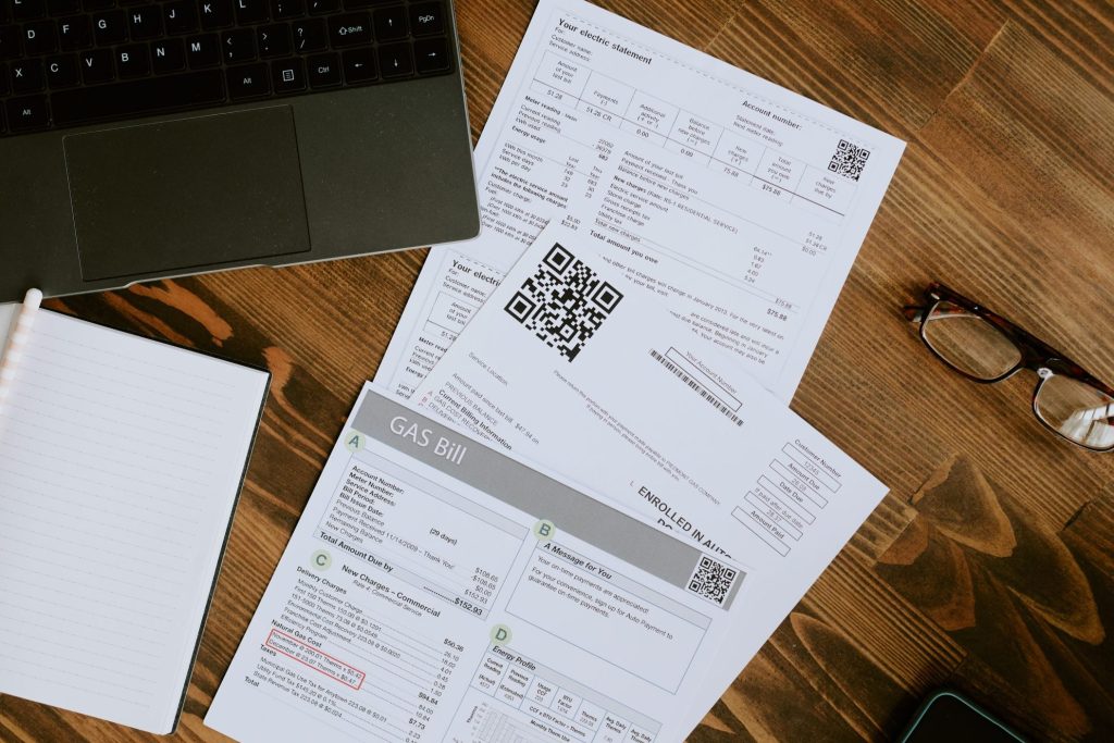 High angle shot of workplace with several docs, glasses and laptop on top of desk made of burnt wood