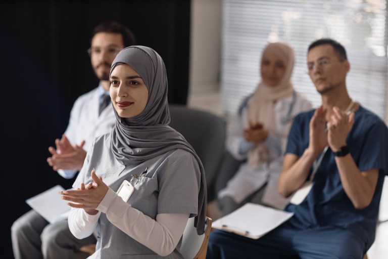 Smiling Female Surgeon Applauding at Conference